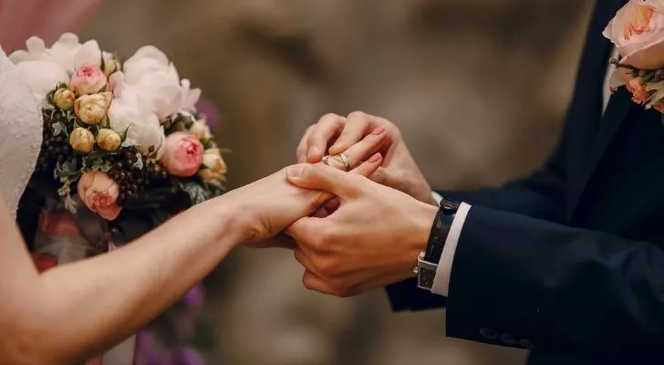 A couple placing rings on each others fingers at their wedding