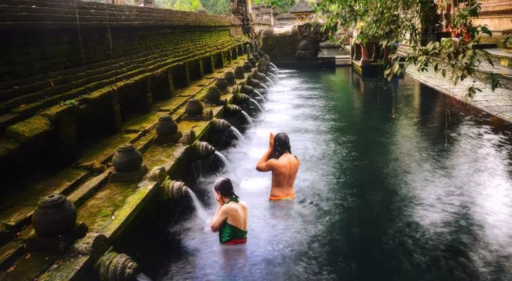 A water pool in a Balinese temple with a row of fountains feeding into it