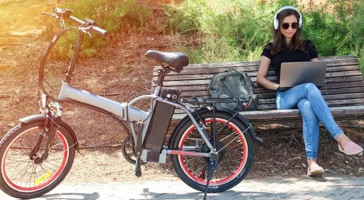An electric bike with a woman working on a bench next to it
