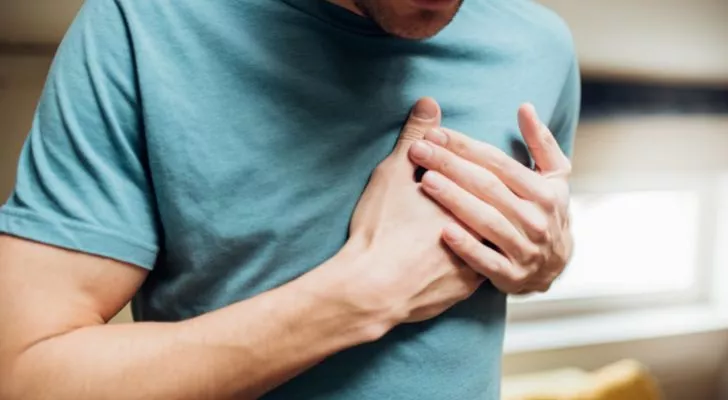A man holding his chest as he has chest pain