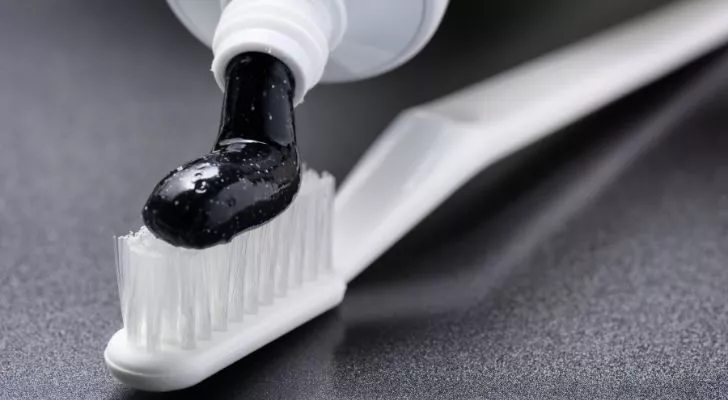 A white toothbrush and black charcoal whitening toothpaste